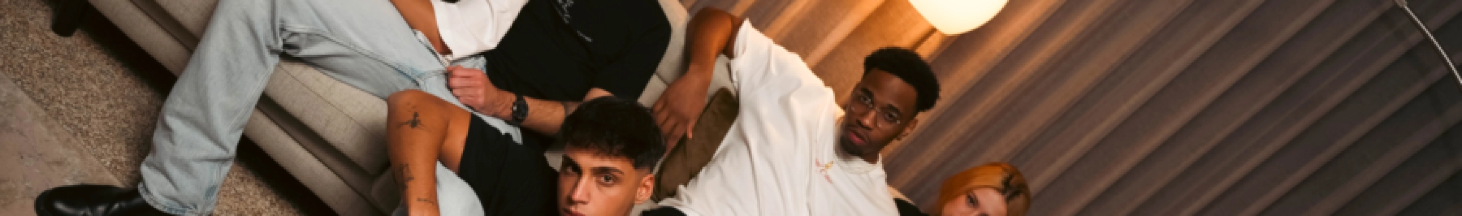 Dropout models showing rebel streetwear energy in oversized tees on a couch